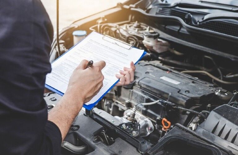 Mechanic checking off items on a list while inspecting an engine