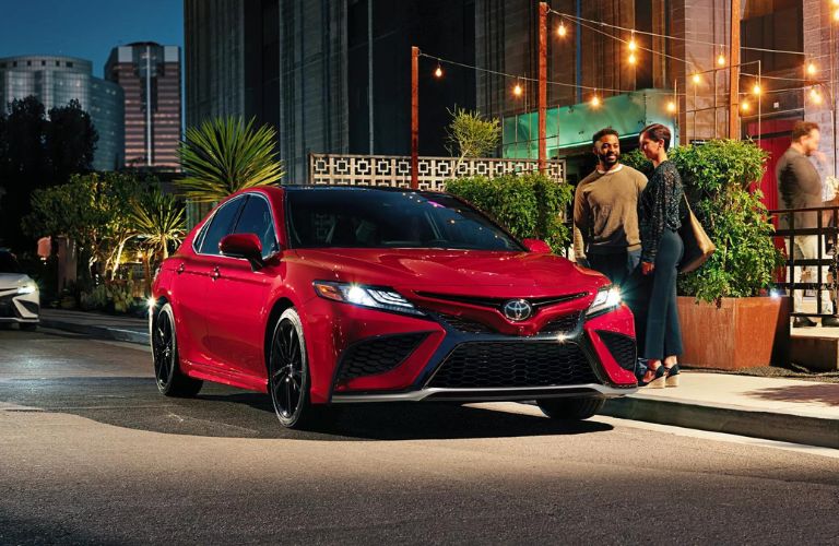 One red color 2024 Toyota Camry is parked outside a building.